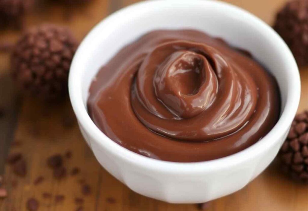Uma tigela pequena cheia de brigadeiro de chocolate cremoso.