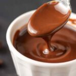 Uma colher é mergulhada em uma sobremesa de chocolate cremosa.