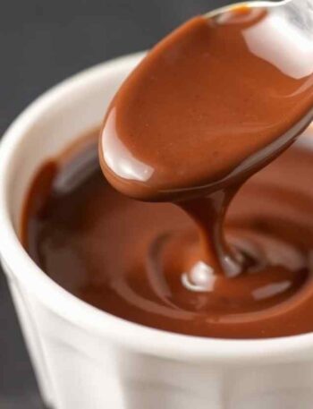 Uma colher é mergulhada em uma sobremesa de chocolate cremosa.