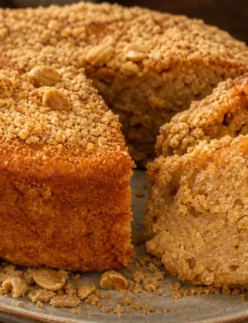 Bolo de paçoca úmido e cheiroso com cobertura de paçoca esfarelada sobre mesa de madeira