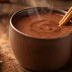 Chocolate quente cremoso com canela em caneca rústica, com vapor suave e textura aveludada