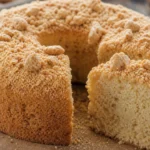 Bolo de paçoca fofinho com paçoca esfarelada por cima sobre mesa de madeira