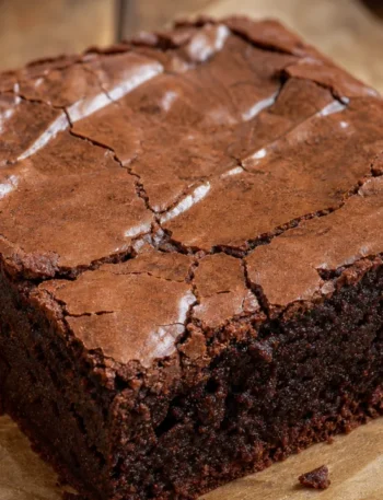 Brownie de achocolatado com casquinha perfeita e interior úmido sobre mesa rústica