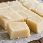 Doce de leite de corte branquinho em pedaços, macio e com textura cremosa sobre papel manteiga