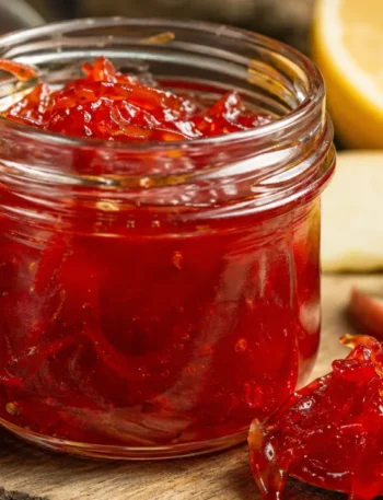 Geleia de pimenta caseira brilhante em pote de vidro com pedaços de pimenta e toque de maçã