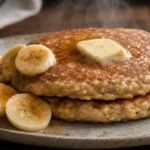 Panqueca de aveia com banana fofinha, dourada e com canela, servida com rodelas de banana em prato rústico