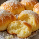 Pão de leite condensado fofinho com leite condensado e coco ralado sobre mesa de madeira