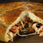 Pão pizza de batata super recheado com mussarela derretida, calabresa, tomate, azeitonas e orégano