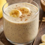 Vitamina caseira de banana com chia e aveia cremosa em copo sobre mesa rústica