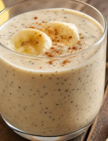 Vitamina caseira de banana com chia e aveia cremosa em copo sobre mesa rústica